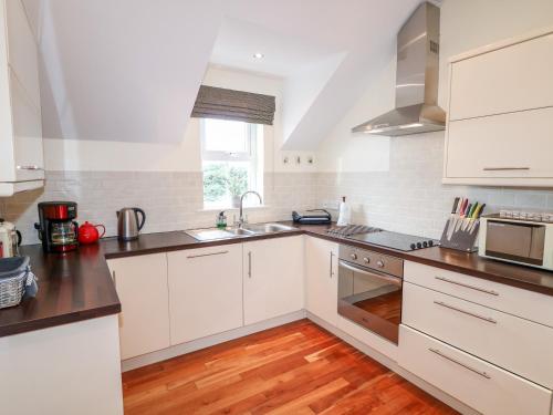 a kitchen with white cabinets and a sink at Seaview in Coleraine