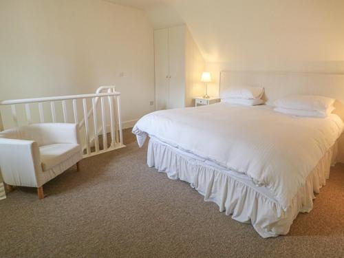 ein Schlafzimmer mit einem großen weißen Bett und einem Stuhl in der Unterkunft Robertson's Cottage in Caledon