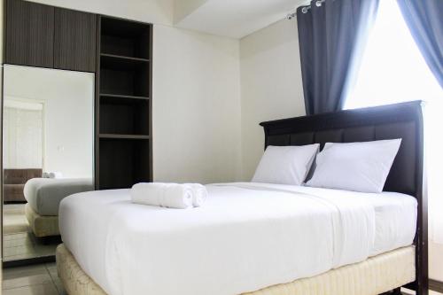 a bedroom with a large white bed with a towel on it at New Furnished 2BR Apartment at Silkwood Residence By Travelio in Tangerang