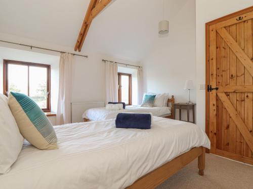 a bedroom with two beds and a wooden door at The Honeypot Cottage in Penzance