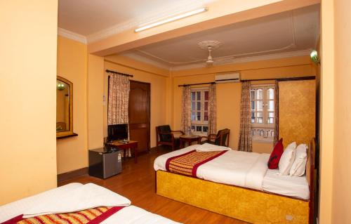 a hotel room with two beds and a desk at Hotel Happy Home or Mudkhu Durbar in Kathmandu