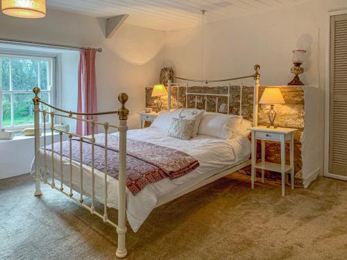 a bedroom with a bed and two lamps and a tub at The Farmhouse in Newport Pembrokeshire