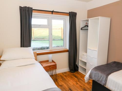 a bedroom with two beds and a window at Glebe Cottage in Dumfries
