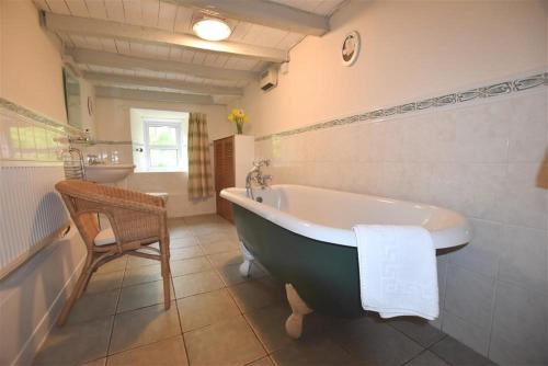 Un baño con bañera, silla y lavabo. en The Farmhouse, en Newport