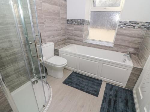 a bathroom with a tub and a toilet and a shower at Rose Cottage in Grange Over Sands
