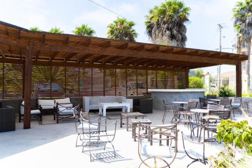 a patio with chairs and tables and a wooden pergola at Hotel Palmas de La Serena in La Serena