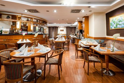 un restaurante con mesas y sillas de madera y un bar en Hotel Kálvária en Győr