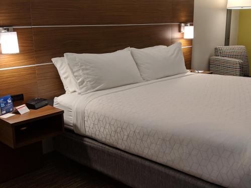 a bed with white sheets and pillows in a hotel room at Holiday Inn Express Hotel & Suites Claypool Hill -Richlands Area by IHG in Pounding Mill