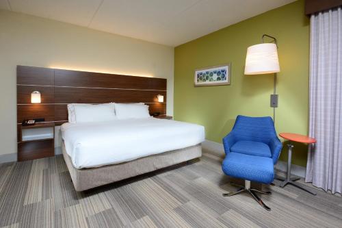 a hotel room with a bed and a blue chair at Holiday Inn Express & Suites Raleigh Durham Airport at RTP by IHG in Durham