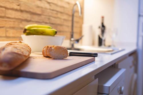 a counter with a cutting board with two loaves of bread at Bravissimo Sacsimort in Girona