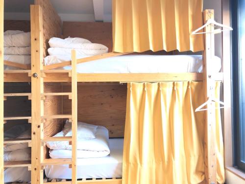 two bunk beds in a room with yellow curtains at ゲストハウスぷれぜんと in Tokyo