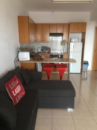 a living room with a black couch and a kitchen at Peyia Paradise Apartment B102 in Peyia
