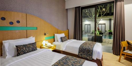 a hotel room with two beds and a large window at ILLIRA Lite Praya Lombok in Praya