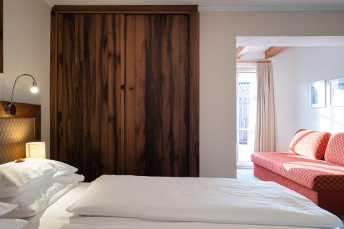a bedroom with a bed and a red couch at Hotel Senningerbräu in Bramberg am Wildkogel