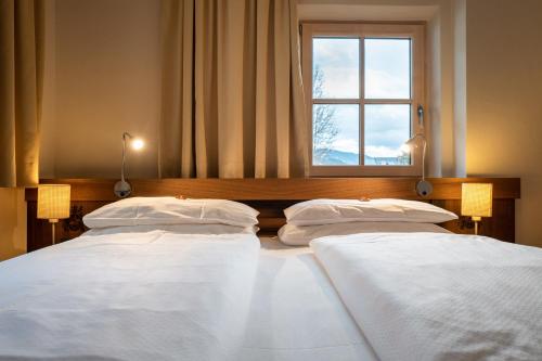 two beds in a room with a window at Hotel Senningerbräu in Bramberg am Wildkogel