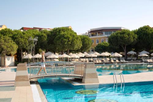 a woman walking across a bridge over a swimming pool at ROBINSON NOBILIS - All inclusive in Belek