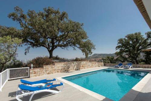 une villa avec une piscine et deux chaises longues dans l'établissement Doña Juana, à El Gastor