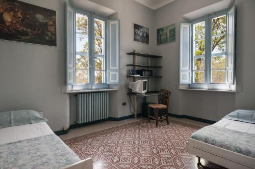 a bedroom with two beds and a tv and two windows at Villa CORALIA D'EPOCA in Osimo