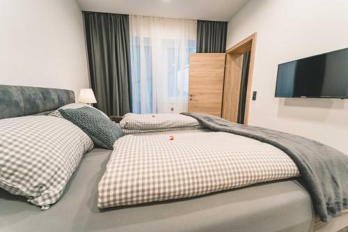 a bedroom with two beds and a tv on the wall at Mirador Apartments in Seefeld in Tirol