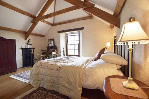 a bedroom with a large bed and a table with a lamp at Panteurig Farmhouse in Goodwick