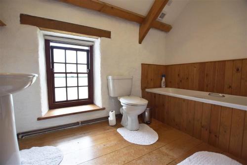 a bathroom with a toilet and a tub and a sink at Panteurig Farmhouse in Goodwick