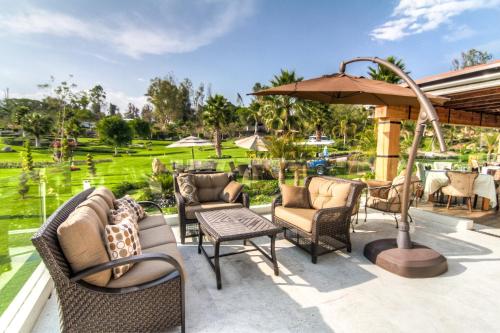 a patio with chairs and tables and an umbrella at Hotel Boutique Matea in Ixtapan de la Sal
