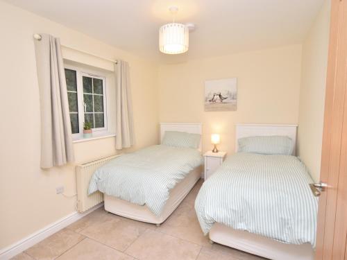 two beds in a room with a window at Lavender Cottage in York