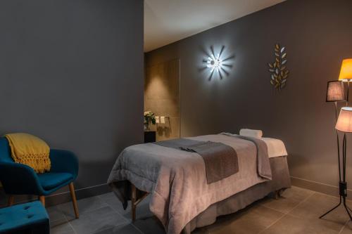 a bedroom with a bed and a chair and a clock at Hotel du Roi & Spa by SOWELL COLLECTION in Carcassonne