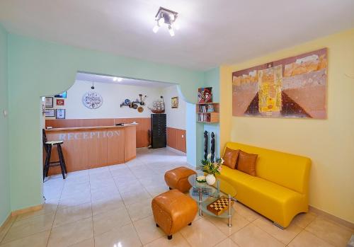 a living room with a yellow couch and a waiting room at Peneka Hotel in Pomorie