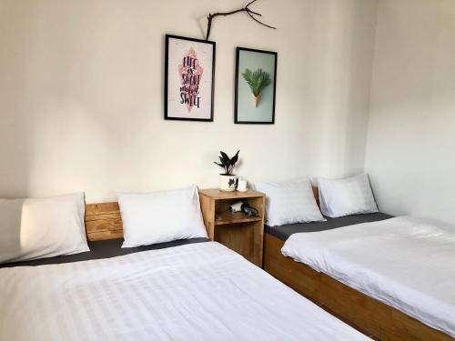two beds in a room with white walls at Len’s hostel in Da Lat