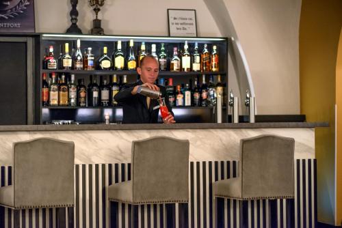a man standing at a bar with a bottle at Hotel du Roi & Spa by SOWELL COLLECTION in Carcassonne