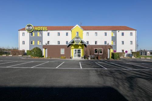 a hotel with a parking lot in front of it at B&B HOTEL Poitiers 1 Futuroscope in Chasseneuil-du-Poitou