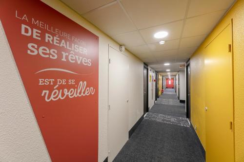 a hallway with a red sign on the wall at B&B HOTEL Poitiers 1 Futuroscope in Chasseneuil-du-Poitou