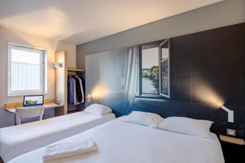 a hotel room with two beds and a window at B&B HOTEL Poitiers 1 Futuroscope in Chasseneuil-du-Poitou