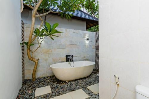 La salle de bains est pourvue d'une baignoire et d'un arbre. dans l'établissement Villa Frangi, à anur