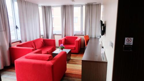 a living room with red chairs and a television at Hotel Richi in Zenica