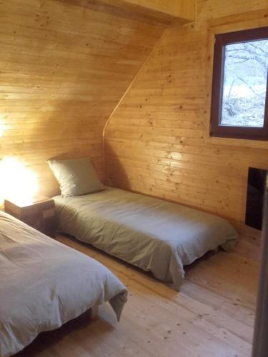 two beds in a log cabin with a window at Le chalet de Magali in Briançonnet