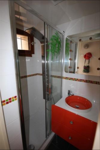 La salle de bains est pourvue d'un lavabo rouge et d'une douche. dans l'établissement Belle villa d'angle, cuisine séjour climatisé, 5 couchages, belle terrasse ombragée, parking dans résidence sécurisée piscine commune à 400m de la mer LRJP23, à Portiragnes