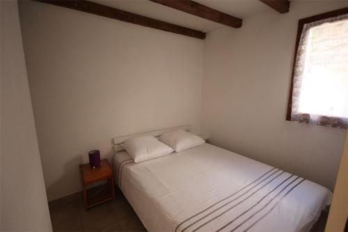 une petite chambre avec un lit blanc et une fenêtre dans l'établissement Belle villa d'angle, cuisine séjour climatisé, 5 couchages, belle terrasse ombragée, parking dans résidence sécurisée piscine commune à 400m de la mer LRJP23, à Portiragnes