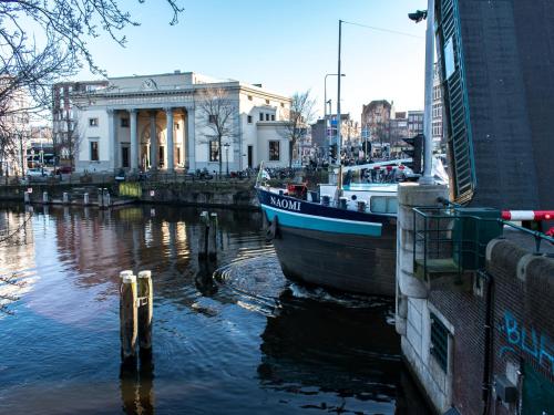 a boat is docked in a river in a city at SWEETS - Willemsbrug in Amsterdam