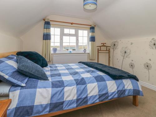 a blue and white bed in a room with a window at Hanging Hill Farm Cottage in Malton