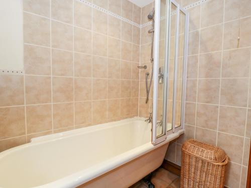 a bathroom with a tub and a shower with a mirror at Chapel Cottage in Stonehouse