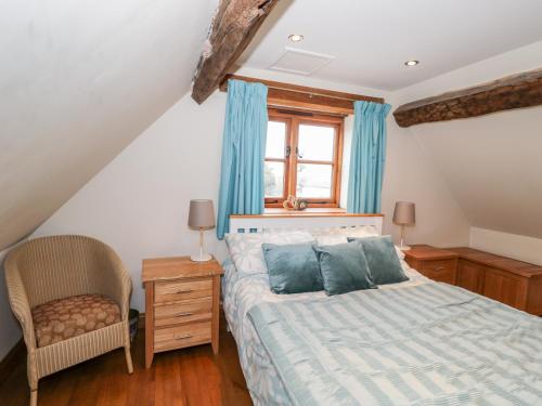 a bedroom with a bed and a chair and a window at Chapel Cottage in Stonehouse