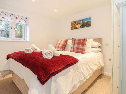 a bedroom with a bed with a red blanket at Bos Lowen in Penzance