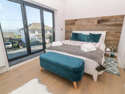 1 dormitorio con 1 cama grande y 1 reposapiés azul en Driftwood Haven, en St Ives