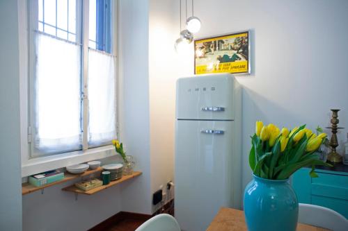 eine blaue Vase mit gelben Tulpen in einer Küche mit Kühlschrank in der Unterkunft Morimondo House: fashion & design in Mailand