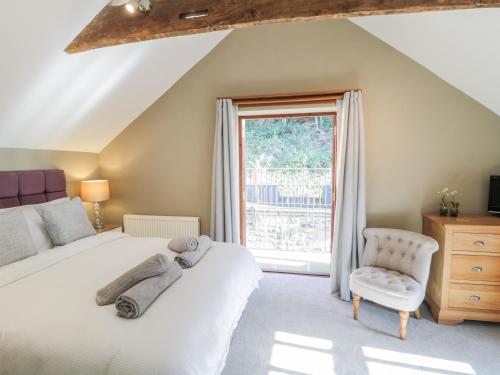 a bedroom with a bed and a chair and a window at Woodside Barn in Thirsk