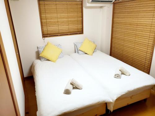 um pequeno quarto com uma cama branca e almofadas amarelas em Takaraboshi room 201 Sannomiya 10 min em Kobe