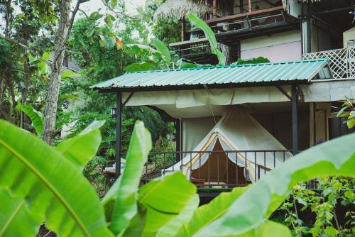 a balcony of a house with a hammock on it at Baansuan Chomchun in Amphoe Mae Taeng