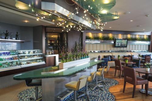 a restaurant with a bar with chairs and tables at Raouche Arjaan by Rotana in Beirut